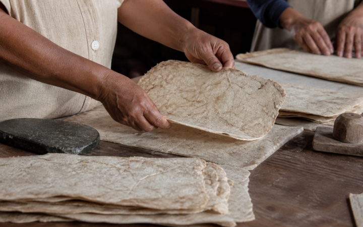 Hojas de papel amate con fibras visibles y diseños vegetales sobre una mesa de taller mexicano